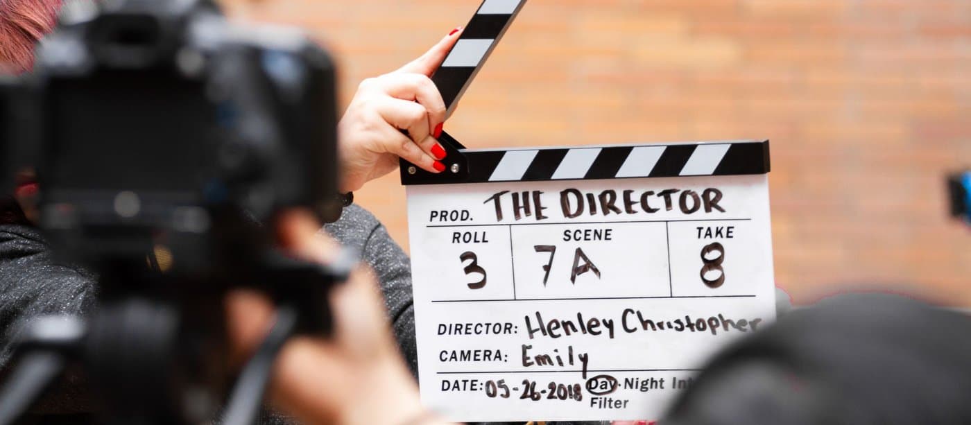A clapperboard held up in front of a camera on set just before a take
