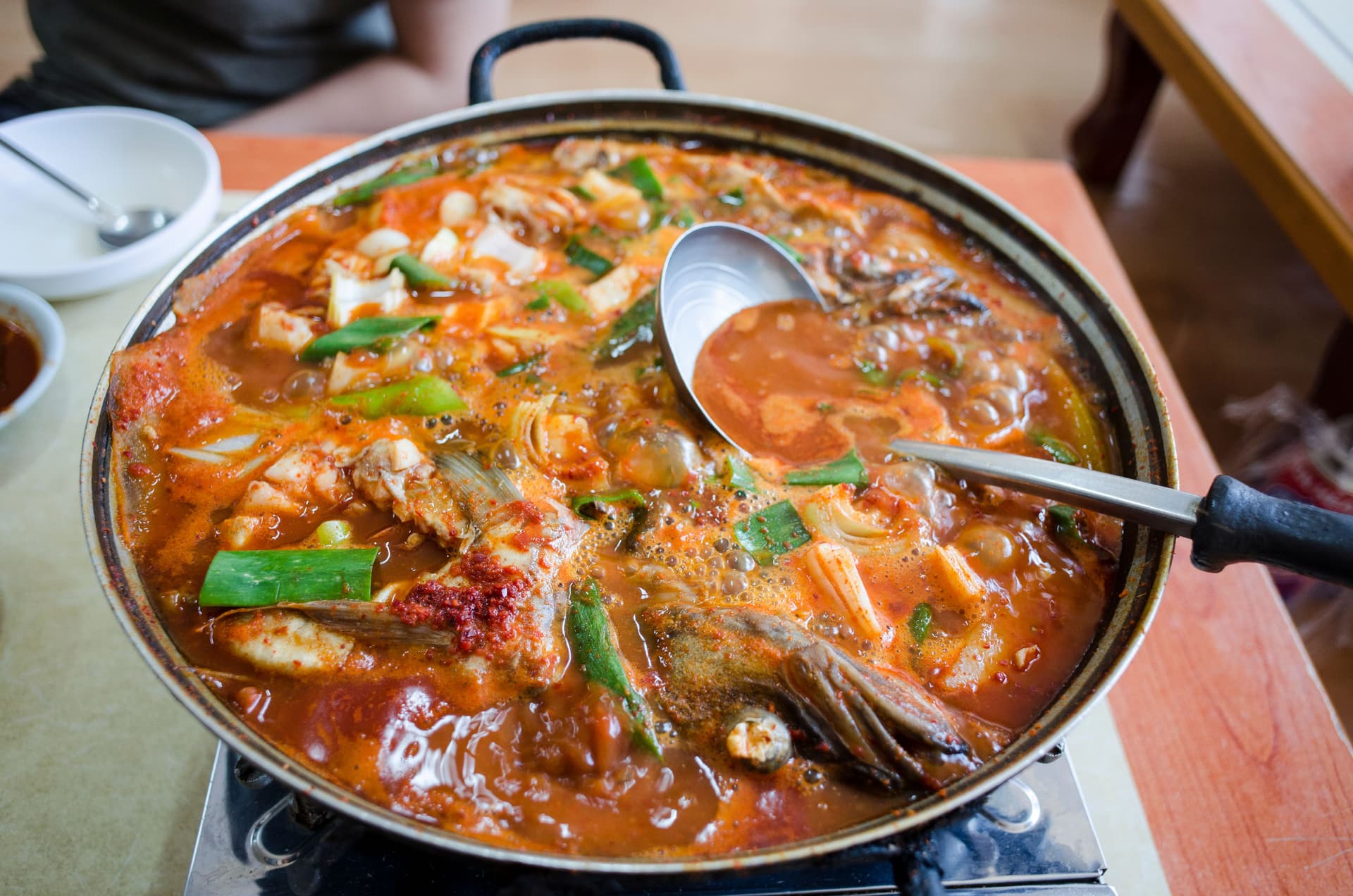 Kimchi jjigae recipe — bubbling Korean kimchi stew with pork and tofu in an earthenware pot