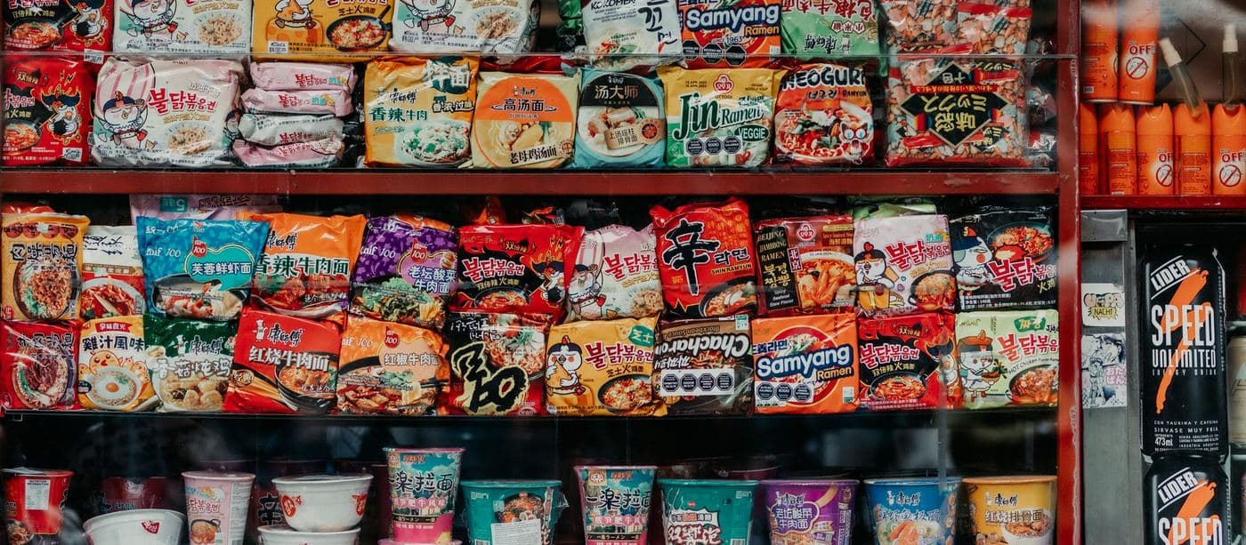 A convenience store wall stacked with Korean instant ramen packets and cup noodles