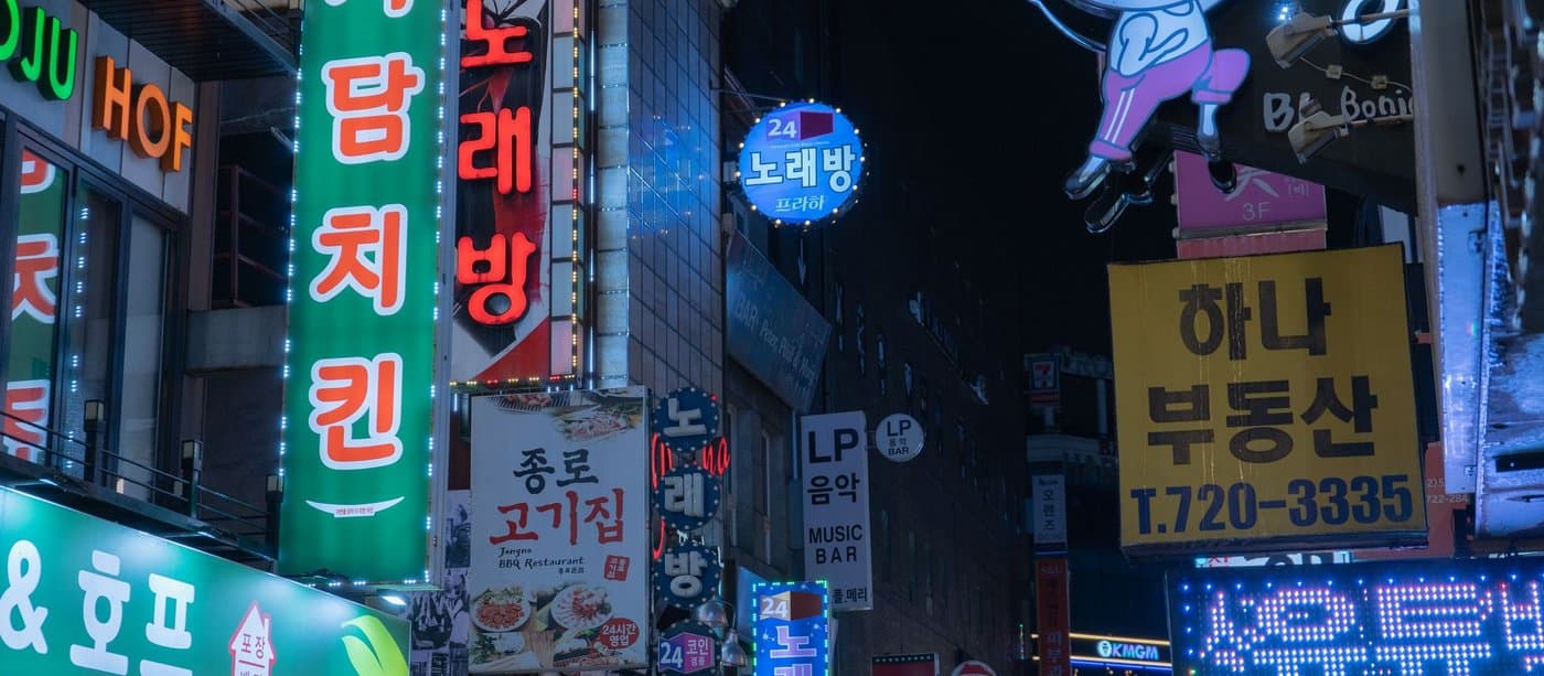 Neon hangul signs stacked up a building facade on a Seoul street at night