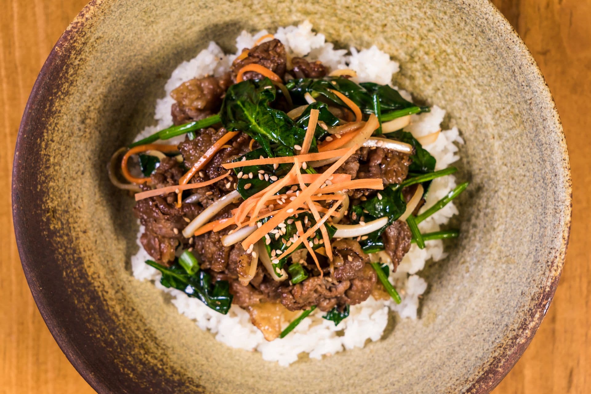 Classic bibimbap recipe bowl — arranged namul vegetables, egg yolk, and gochujang before mixing